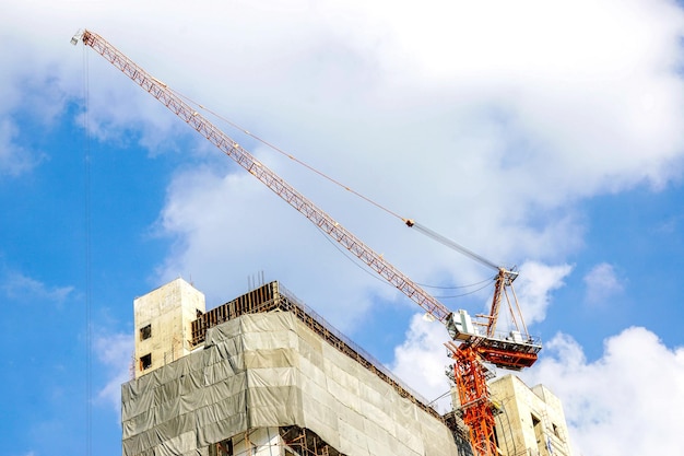 Gebouw in aanbouw met hijskranen op heldere blauwe hemelachtergrond