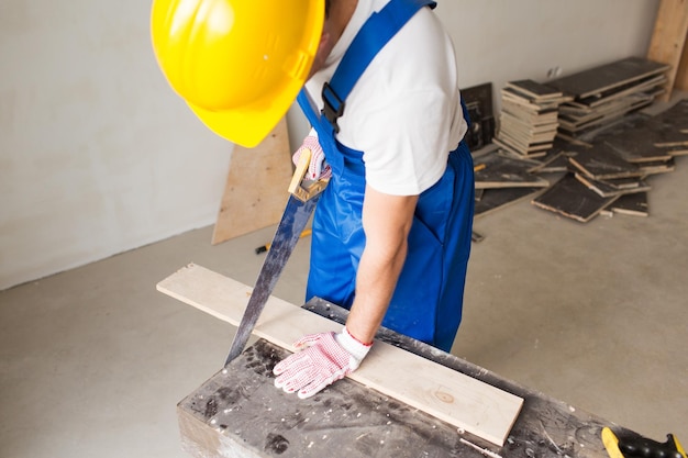 Gebouw, timmerwerk, reparatie, teamwork en mensenconcept - close-up van bouwer met armzaagzaagbord op tafel