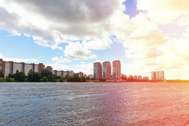 Gebouwen aan de rivier en de lucht met witte cumuluswolken. Baailandschap, schittering van de zon - Neva, Rusland, Sint-Petersburg, juli 2021