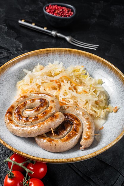 Gebraden Beierse spiraal vlees worstjes op een bord met zuurkool Zwarte achtergrond Top view