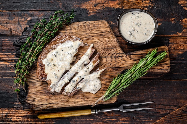 Gebraden filet rundvlees biefstuk met pepersaus op houten bord