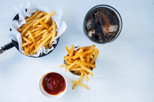 Gebraden frieten en ketchup met frisdranken op een lijst