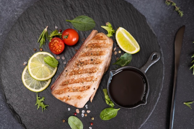 Gebraden gekookt stuk tonijnfilet op een serveerbord van zwarte steen