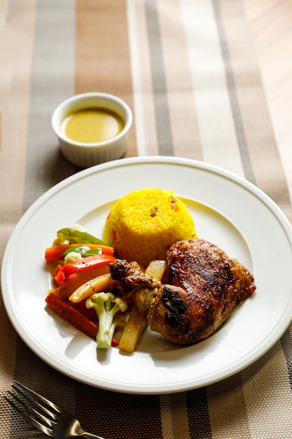 Gebraden kip met kruiden rijst met salade dip lepel en vork geserveerd op een bord geïsoleerd op servet zijkant van fastfood op tafel