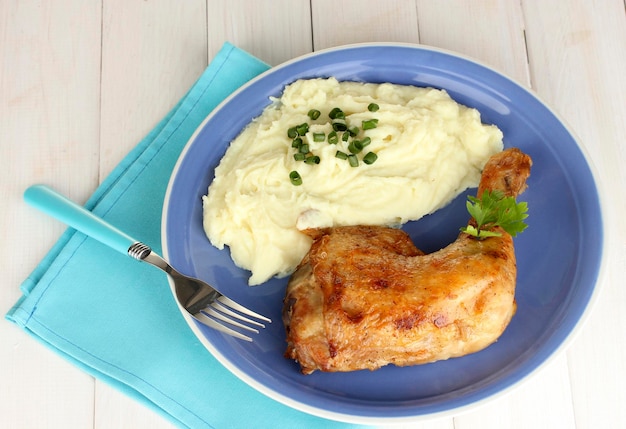 gebraden kippenbeen met aardappelpuree op het bord op een witte houten tafel close-up