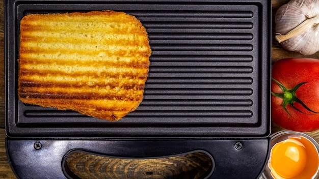 Foto gebraden wit toastbrood met gouden korst in strepen ligt in een open zwarte boterhammachine