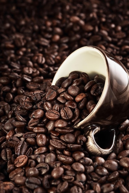 Gebrande koffiebonen en koffiekopje op textuur van koffiebonen klaar om te drinken selectieve focus roosteren en bereiden van koffie verticaal frame