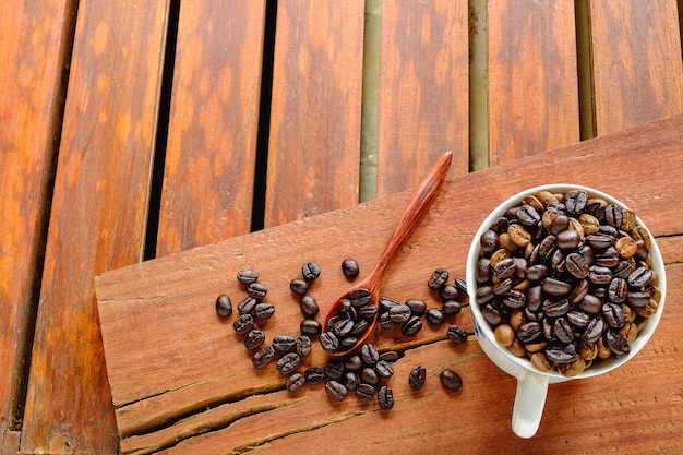 Gebrande koffiebonen in een kopje koffie op een houten tafel.