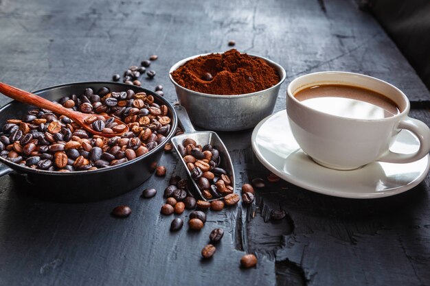 Gebrande koffiebonen met koffiepoeder en koffiekopjes.