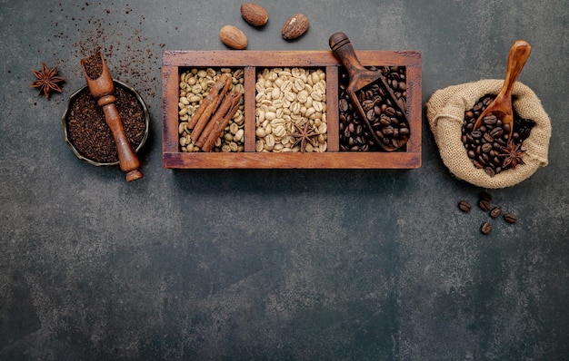 Gebrande koffiebonen met koffiepoeder en smaakvolle ingrediënten voor het maken van smakelijke koffie-opstelling op donkere stenen achtergrond