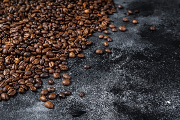 Gebrande koffiebonen op rustieke tafel. Zwarte achtergrond. Bovenaanzicht. Ruimte kopiëren.