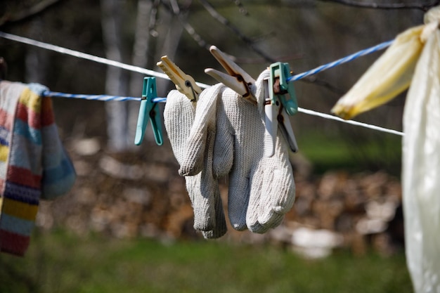 Foto gebreide handschoenen die aan een waslijn hangen en vastgemaakt zijn met wasknijpers