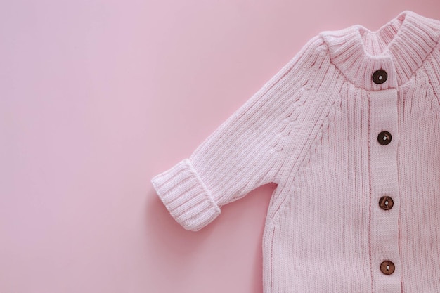 Gebreide jumpsuit voor een pasgeborene op een roze achtergrond Buitenkleding voor peuters voor wandelingen in de herfst of lente