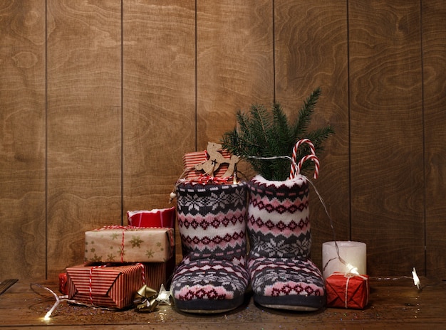 Gebreide kerstlaarzen op een houten achtergrond rond geschenken