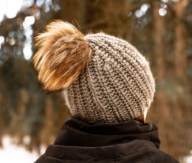 Gebreide muts met pluizige pompon achterkant zicht op vrouwelijk hoofd buiten in de winter natuur