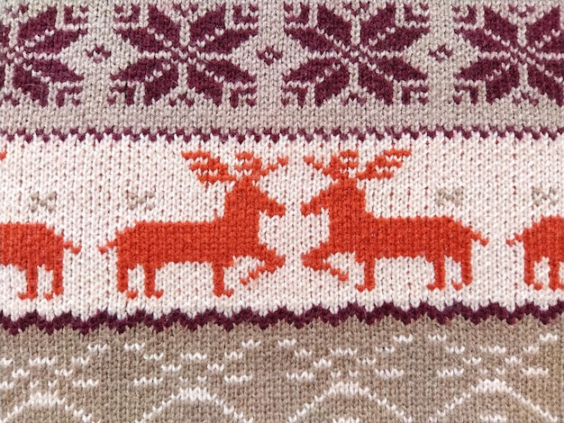 Gebreide patronen met sneeuwvlokken herten bloemen gebroken strepen Oranje rood bruin wit beige wollen draden Volkskunst Warme wintertrui gebreid met lussen aan de voorkant Nieuwjaar en Kerstmis