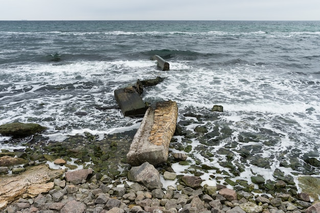 Gebroken betonplaten op de rotsachtige kust