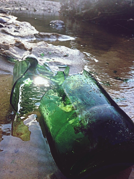 Foto gebroken fles in het water op het strand.