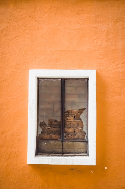 Gebroken glas in raam op oranje kleur gips cement muur met wit frame omhulsel venster. gebroken of gebarsten venster.