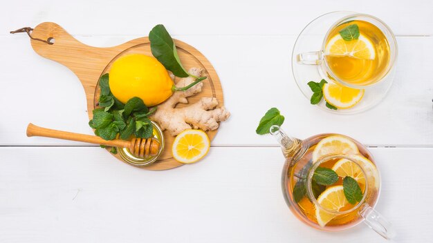 Gebrouwen thee in een theepot en een kopje Dichtbij zijn de ingrediënten voor het maken van gezonde thee