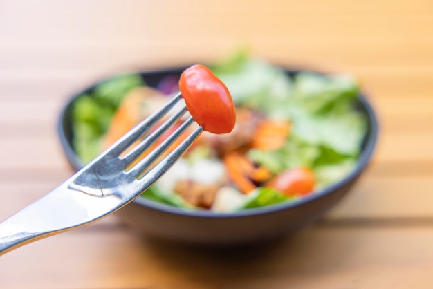 Gebruik een vork een tomatenspies op de voorgrond en een salade op de achtergrond Ontbijtsalade