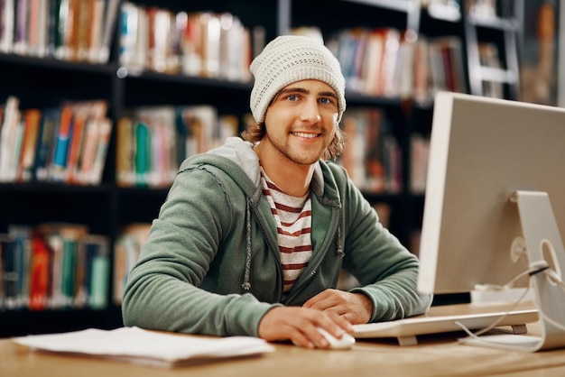 Gebruik maken van de studiehulpmiddelen die tot mijn beschikking staan Bijgesneden portret van een jonge mannelijke universiteitsstudent die in de bibliotheek studeert