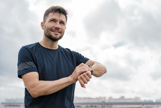 Gebruikt een fitness horloge meet de tijd een sportieve mannelijke atleet training doet warm-up oefeningen