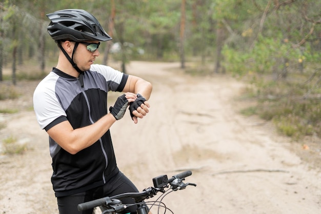 Gebruikt een fitnesshorloge een fietser op een mountainbike in een helm en uitrusting ecotoerisme