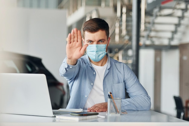 Gebruikt laptop Jonge man in wit overhemd en blauwe jas werkt binnenshuis