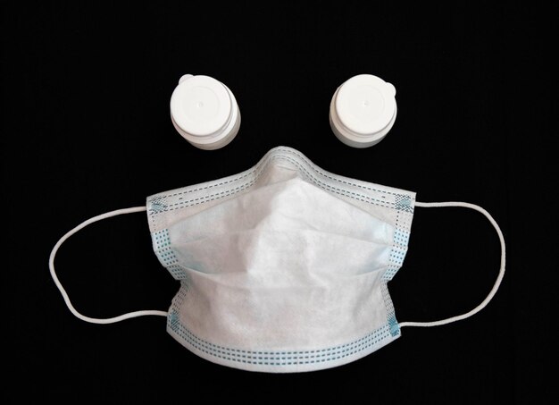 Gebruikt medisch masker met twee medicijnflessen op een zwarte achtergrond