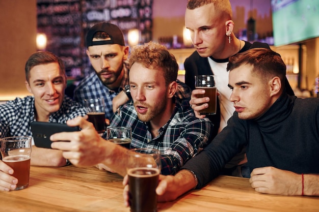 Gebruikt telefoon Groep mensen samen binnen in de kroeg veel plezier in het weekend