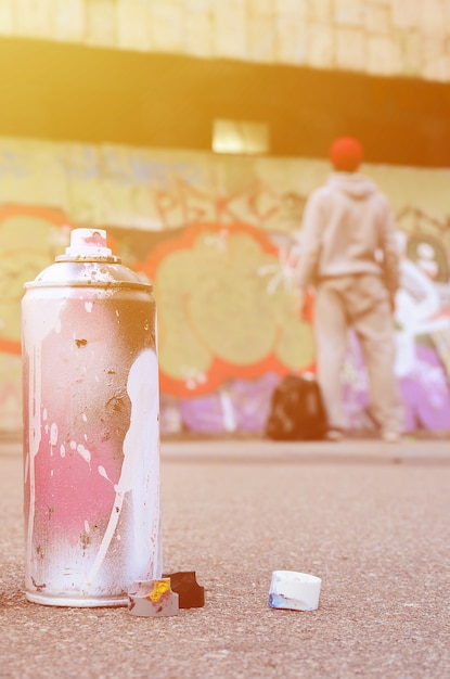 Gebruikte aerosol verfspuitbus met roze en witte verf op het asfalt