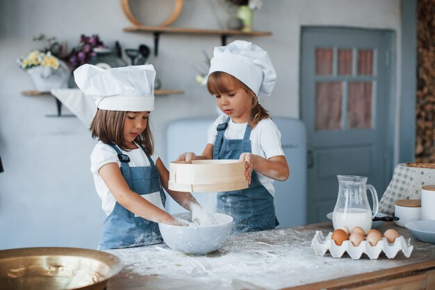 Gebruikte zeef. Familie kinderen in witte chef-kok uniform bereiden van voedsel in de keuken.