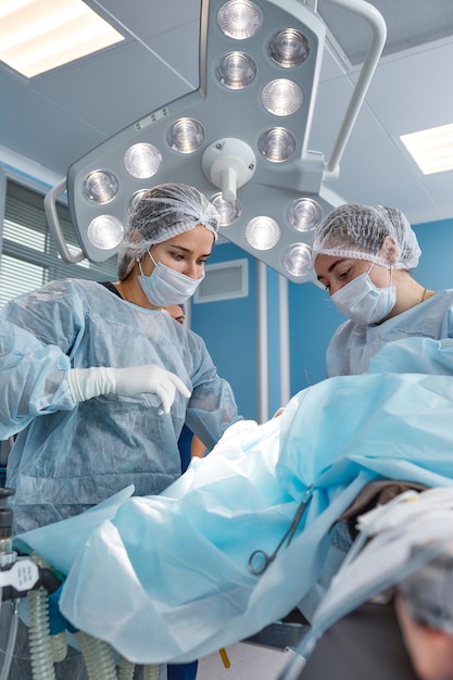 Foto geconcentreerd chirurgisch team dat een patiënt bedient in een operatiekamer goed opgeleide anesthesist met jarenlange training met complexe machines volgt de patiënt tijdens de operatie