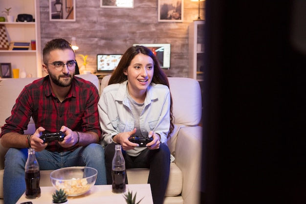 Geconcentreerd jong stel tijdens het spelen van videogames op televisie. Paar zittend op de Bank.