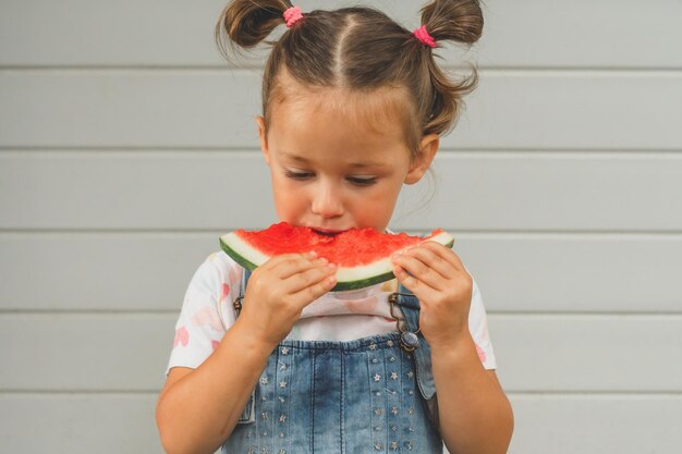 Geconcentreerd meisje van 34 jaar oud met twee paardenstaarten eet watermeloen Zomeroogst vitamine zoet gezond fruit