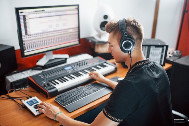 Geconcentreerd op het werk. Geluidstechnicus in koptelefoon die binnen in de studio werkt en muziek mixt.