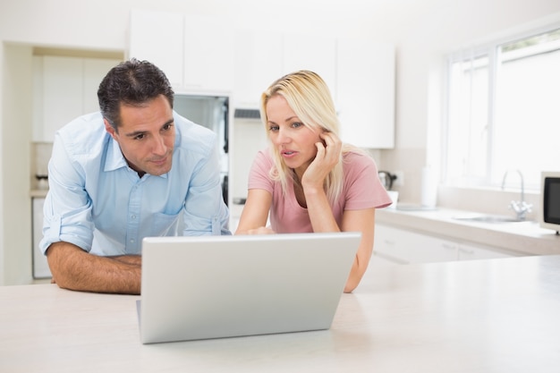 Geconcentreerd paar die laptop in keuken met behulp van