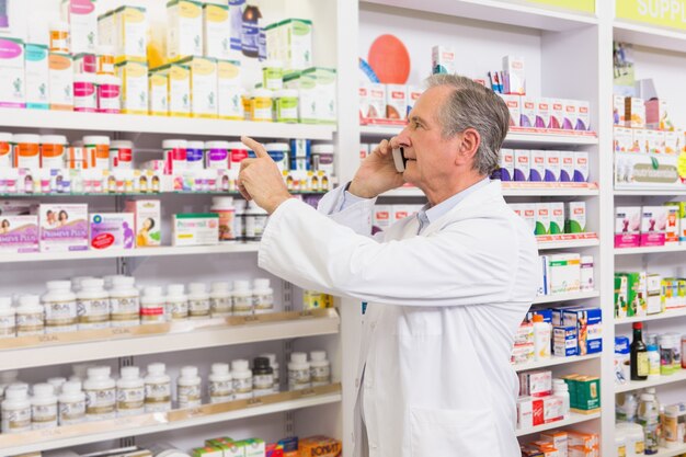 Geconcentreerde apotheker op de telefoon wijzend medicijn