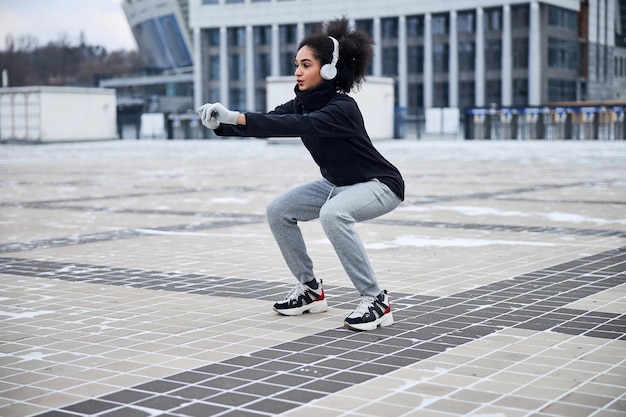 Geconcentreerde atleet die squats doet op een plein