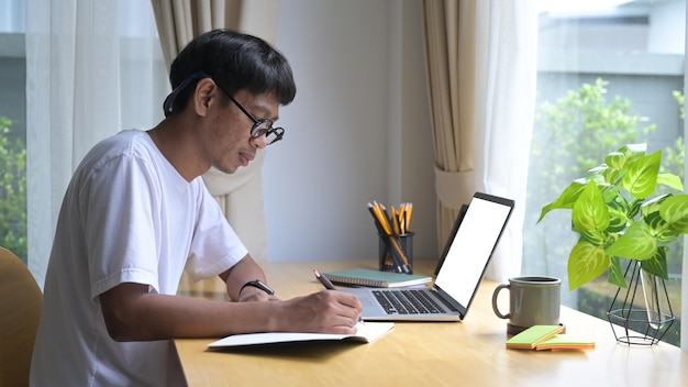 Geconcentreerde Aziatische man die online vanuit huis werkt met een computerlaptop