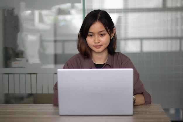 Geconcentreerde aziatische vrouw die overdag laptop op kantoor gebruikt