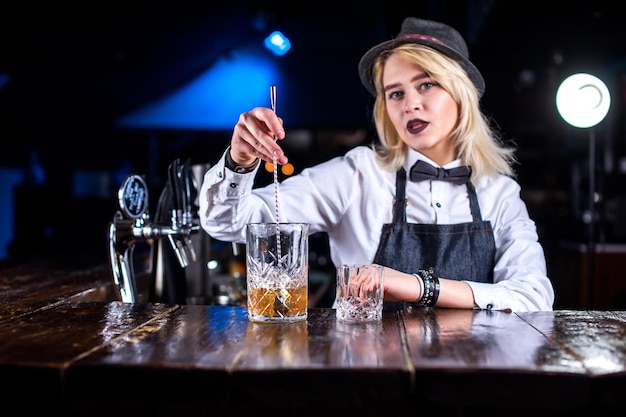 Geconcentreerde bartending die verse alcoholische drank in de glazen achter de bar giet