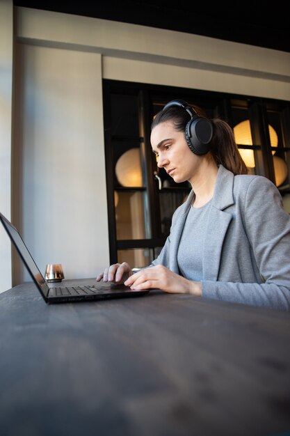 Geconcentreerde blanke zakenvrouw werkt met laptop en koptelefoon op kantoor.