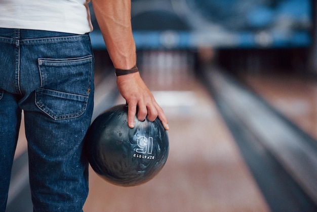 Foto geconcentreerde foto achterkant deeltjesbeeld van een man in casual kleding die bowlen speelt in de club