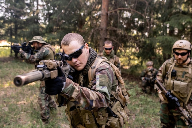 Geconcentreerde gewapende soldaten in uniform die geweren dragen en bosterrein onderzoeken