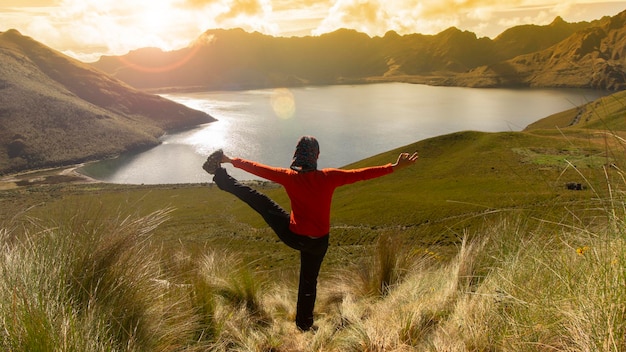 Geconcentreerde jonge Latijns-Amerikaanse vrouw die alleen yoga beoefent voor de mojanda lagune.