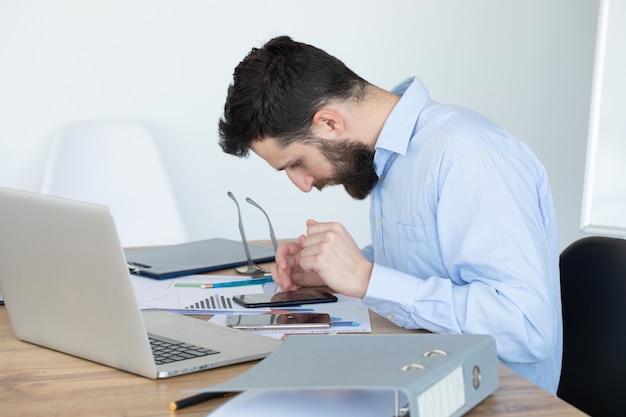 Geconcentreerde jonge man aan het werk op laptop thuis kantoor