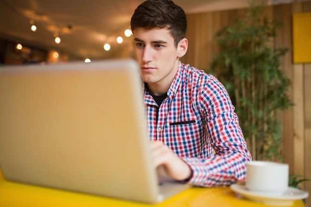 Geconcentreerde jonge man met behulp van laptop