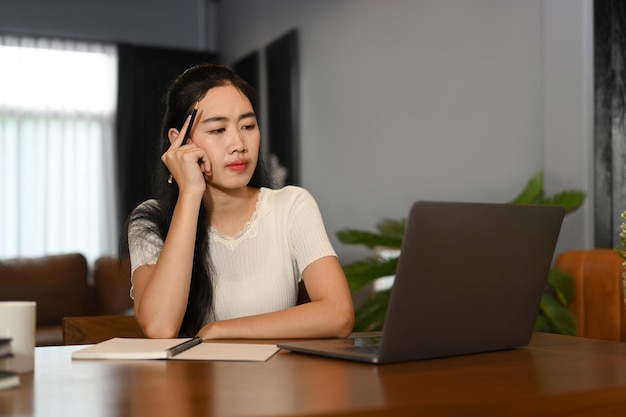 Geconcentreerde jonge vrouw die naar computertablet kijkt terwijl ze online studeert op virtuele webklasse thuis elearning onderwijsconcept